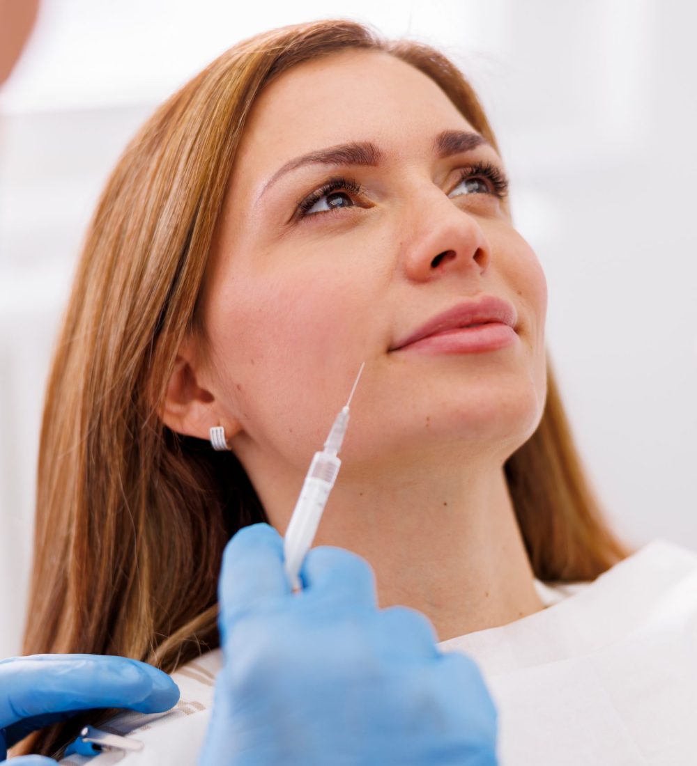 Woman having beauty treatment at doctor office, doctor applying hyaluron fillers